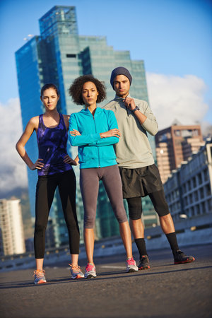 Were going to own these streets. Portrait of three young joggers standing in an empty road in the city.の写真素材