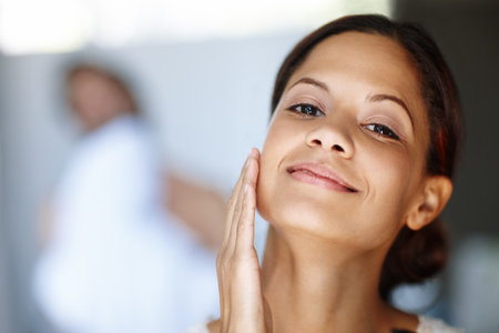 My skin feels so smooth...An attractive young woman taking care of her skin in the morning with a smile.の写真素材