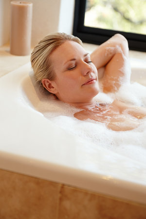 Let the bubbles melt your stress away. A happy young woman relaxing in a luxurious foam bath.