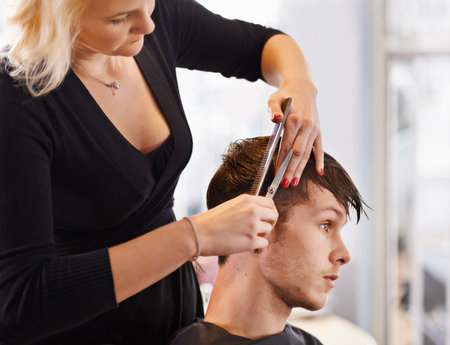 Getting a stylish haircut. a young man having his hair cut by a stylist.の写真素材