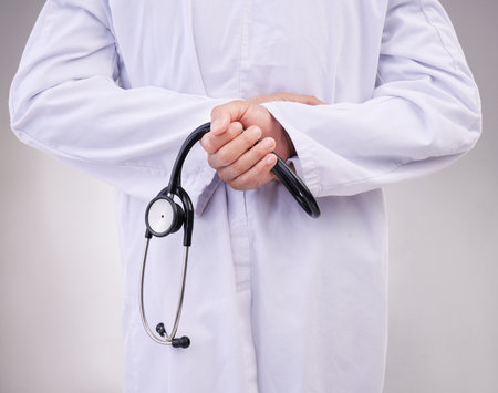 Medical, stethoscope and back with hands of doctor in studio for healthcare, cardiology and checkup. Medicine, support and expert with man on gray background for advice, heartbeat and consultingの写真素材