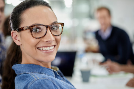 My work life is looking great. Closeup portrait of a smiling businesswoman with office space and colleagues in the background.の写真素材