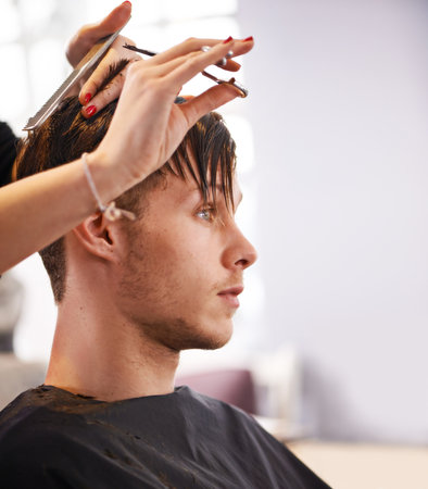 Trimmed to perfection. a man having his hair cut at a hair salon.の写真素材
