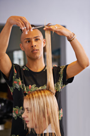 Letting an expert handle her hair. a male hairdresser cutting a clients hair.の写真素材