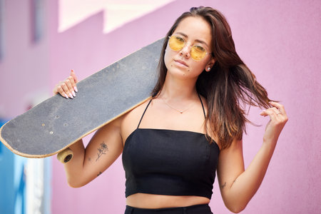 Portrait of woman, sunglasses and skateboard retro look in urban city on street style adventure. Young asian trendy skater girl, gen z or millennial lifestyle and fun modern edgy fashion outdoorsの写真素材