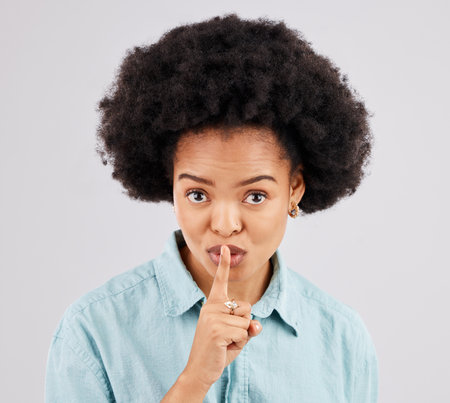 Secret, portrait and woman with finger on lips in studio, white background and privacy sign. Face of female model, silence and shush for quiet, gossip and whisper emoji for confidential mystery newsの写真素材