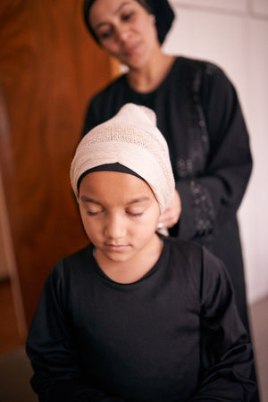 Passing on tradition. a mother helping her daughter put on a headscarf.の写真素材