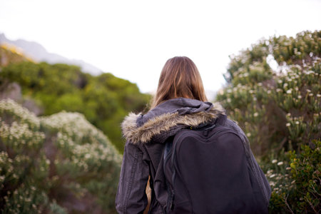 Heading into nature. Rearview shot of a young woman hiking through nature.の写真素材