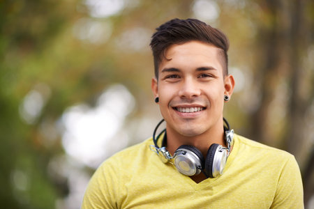 Enjoying some music and fresh air. Portrait of a handsome young man with headphones around his neck.の写真素材