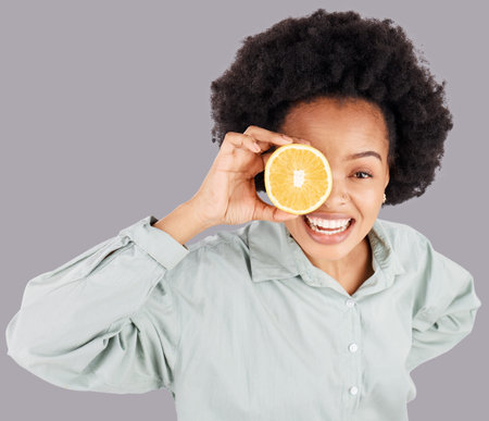 Portrait, orange and black woman smile with fruits in studio isolated on a gray background. Food, top view and happiness of person with vitamin c, nutrition or healthy diet, citrus or vegan detox.の写真素材