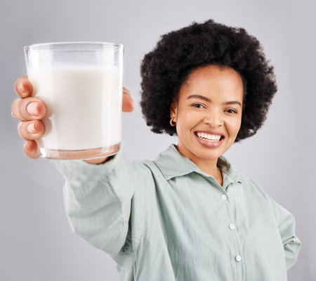 Portrait, happy woman and glass of milk in studio, white background and backdrop for healthy diet. Female model, food and calcium of smoothie, vanilla milkshake and nutrition of weight loss drinkの写真素材