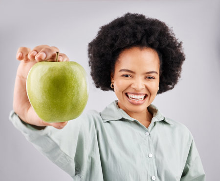 Portrait, apple and black woman smile in studio isolated on a white background. Food, fruit and happiness of person with vitamin c, nutrition or healthy diet, wellness or nutritionist, vegan or detoxの写真素材