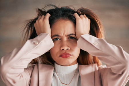 Portrait, stress and woman in office with anxiety, problem or mental health issue on wall background. Frustrated, lady and face of corporate employee suffering burnout, angry or headache from vertigoの写真素材