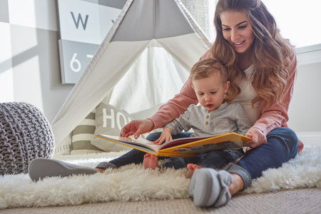 He loves a good story. a woman reading to her toddler son at home.の写真素材