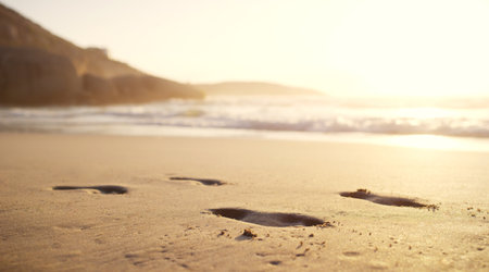 The spot of true lovers. Still life shot of footsteps on the beach sand at sunset.の写真素材