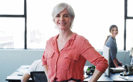 My team is going to take this company places. Portrait of a confident mature businesswoman working in a modern office with her colleagues in the background.の写真素材