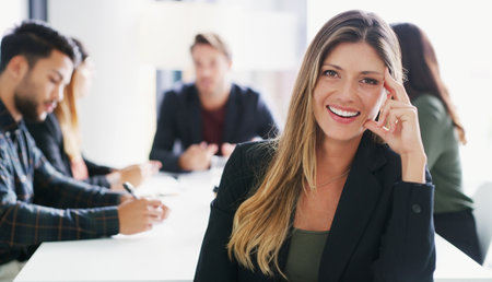 My team have been so amazing. Portrait of a young businesswoman sitting in an office with her colleagues in the background.の写真素材