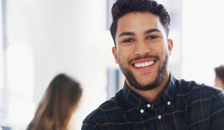 Confidence has taken me very far. Portrait of a young businessman sitting in an office with his colleagues in the background.の写真素材
