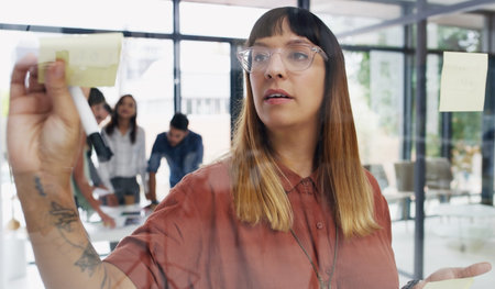 This looks like a solid plan to me. a young businesswoman brainstorming with notes on a glass wall...
