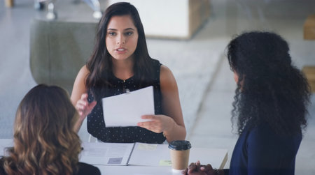 Its a matter of paperwork. High angle shot of three young businesswoman sitting in the boardroom during a management meeting.の写真素材