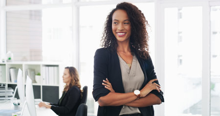 So many ideas for business growth. Portrait of a confident young businesswoman working in a modern office with her colleague in the background.の写真素材