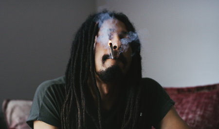 This is what I do to relax. a young man smoking a marijuana joint at home.の写真素材