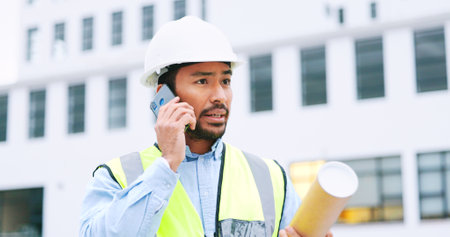 Civil engineer on a phone call while at a construction site discussing a strategy and plan to work on. Close up portrait of confident architect talking with building in the background and copy spaceの写真素材