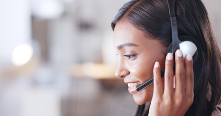 Call center agent helping client in a phone call giving great customer service. Customer support employee consulting clients online using headset. Professional friendly woman working at her deskの写真素材