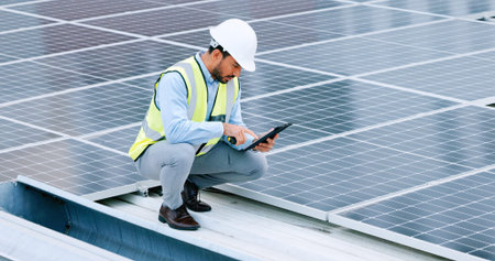 Young engineer or contractor inspecting solar panels on a roof in the city. One confident young...