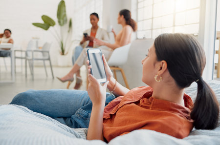 Creative businesswoman, designer or digital marketing agency employee on her phone browsing and searching on a break. Female worker reading or looking for ideas for social media trends on bean bag.の写真素材
