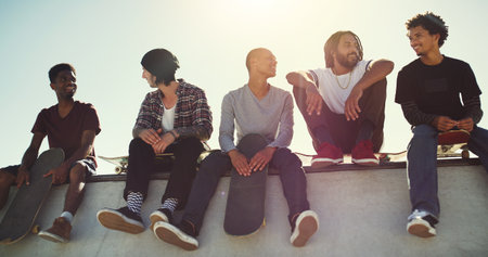 Fun day in the sun with the boys. Full length shot of a group of friends sitting together on a ramp at a skatepark.の写真素材