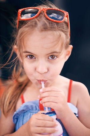 Enjoying a delicious dairy drink. a little girl drinking a beverage outdoors.の写真素材