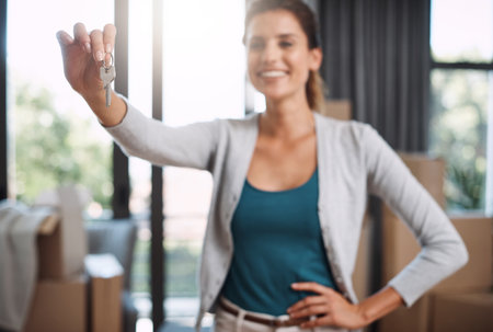 This one key is all I need. an attractive young woman holding the key to her new home while moving in.の写真素材