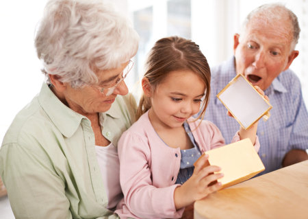 Grandparents spoil grandkids. a senior couple giving a gift to their granddaughter.の写真素材