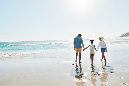 Summer, the best season for a family vacation. an adorable little girl going for a walk with her parents on the beach.の写真素材