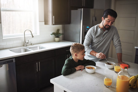 Starting off the day properly. High angle shot of a young boy and his father having breakfast in the kitchen.の写真素材