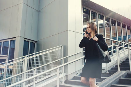 Just success, nothing less. a young businesswoman using a mobile phone while walking through the city.の写真素材