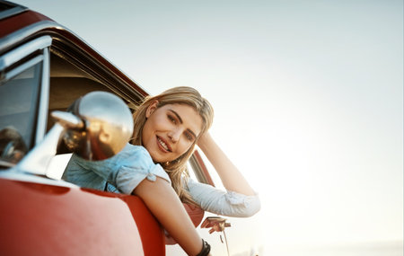 The ultimate summer activity, a road trip. Portrait of a beautiful young woman going on a summers road trip.の写真素材