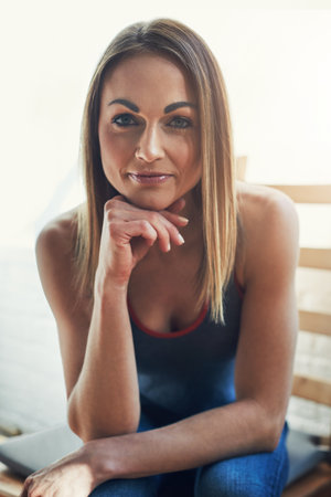 Fitness and focus go hand in hand. Cropped portrait of an attractive young sportswoman looking thoughtful while sitting on a wooden chair.の写真素材