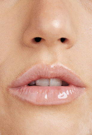 Lips, makeup and beauty of woman with lipstick for shine and natural glow on skin. Face, mouth and nose zoom of aesthetic model for self care, skincare and body wellness cosmetics or collagen fillerの写真素材
