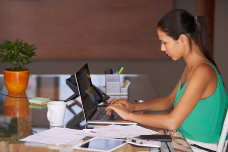 She learnt the value of hard work by working hard. A young woman hard at work sitting in her home office.の写真素材