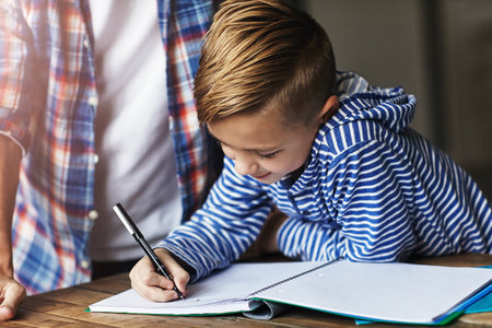 He always does his homework on time. a little boy doing his homework with his father at home.の写真素材