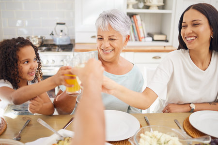 Orange juice, celebration and family breakfast with child and grandmother for wellness, healthy life and growth development. Senior woman, girl kid or people doing drink cheers at home holiday brunchの写真素材