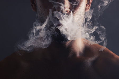 Smoke, cloud and face of man with pollution for marijuana smoker health campaign with zoom. Cannabis, weed and cbd addiction model for smoking habit lifestyle advertising in black studio.の写真素材
