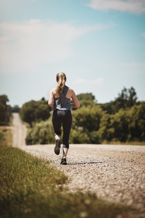 Crush your fitness goals one step at a time. Rearview shot of a young woman out on a trail run.の写真素材