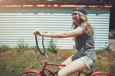Happy as long as Im on my bike. an attractive young woman riding a bicycle outdoors.の写真素材