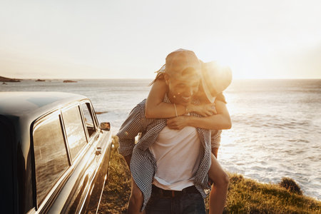 Making it a road trip to remember. a happy young couple enjoying a piggyback ride on a road trip.の写真素材