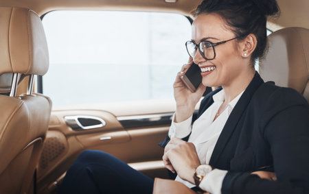 Yes this her speaking. a confident young business woman seated in a car as a passenger and talking on her cellphone while going to work.の写真素材
