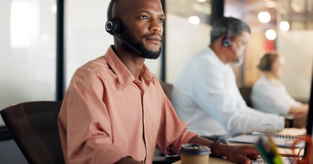 Call center, customer support and face of a black man consultant doing online consultation in the office. Customer service, sales employee and telemarketing agent working on crm strategy in workplaceの写真素材