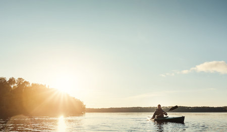 Everything you need. a young man kayaking on a lake outdoors.の写真素材